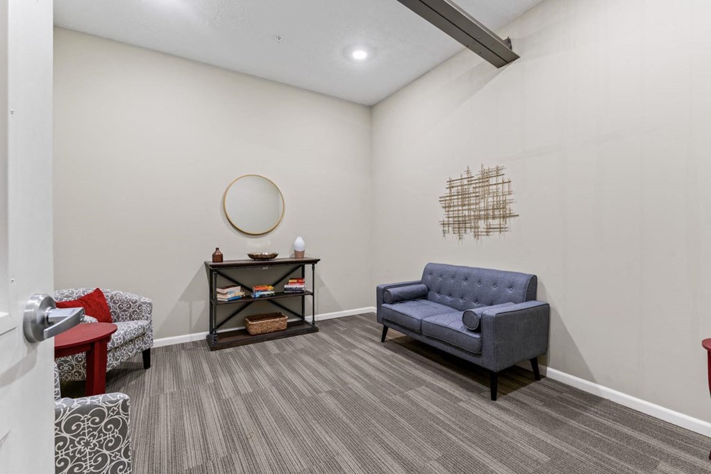 a living room with a blue chair and a mirror on the wall