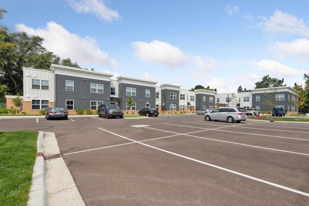 a parking lot with cars in front of an apartment complex
