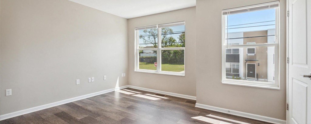 a bedroom with hardwood floors and two large windows