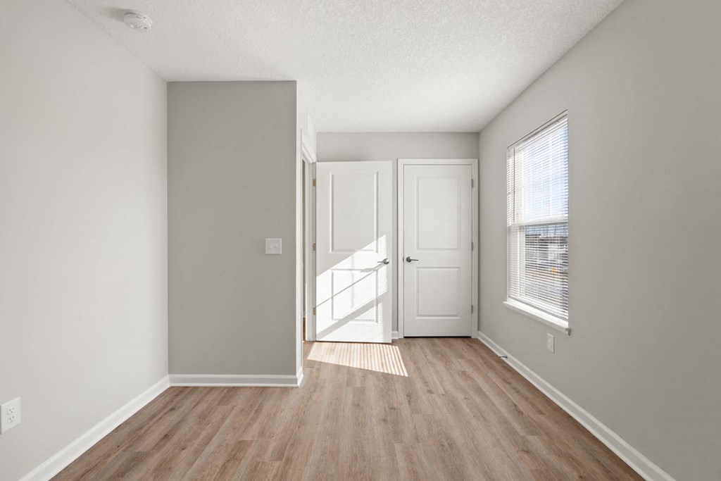 A room with a white door and a window with blinds.