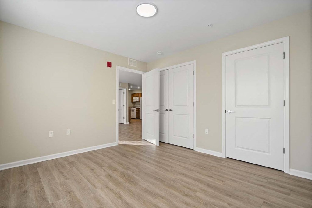 an empty room with three doors and a wood floor