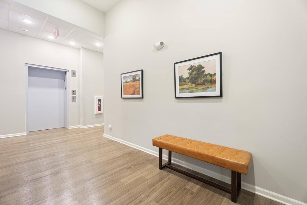 A room with a bench and two pictures on the wall.