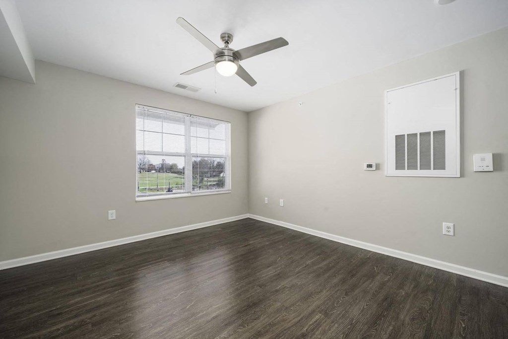 an empty living room with a ceiling fan and a window