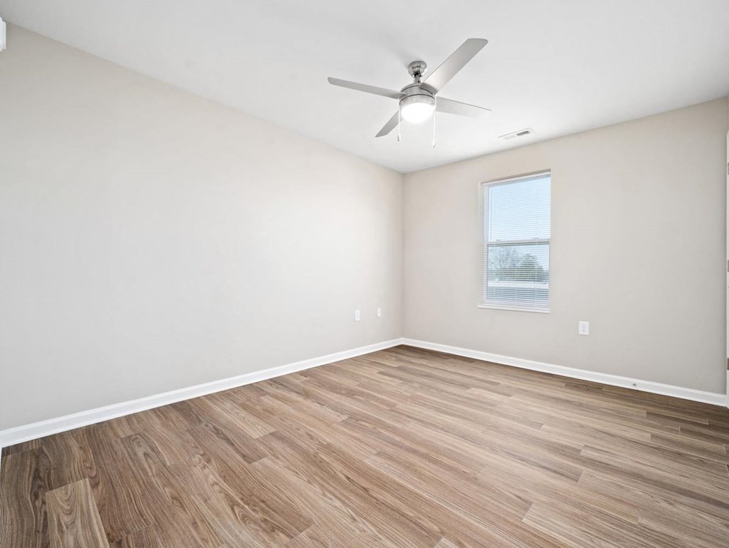an empty living room with a ceiling fan and a window