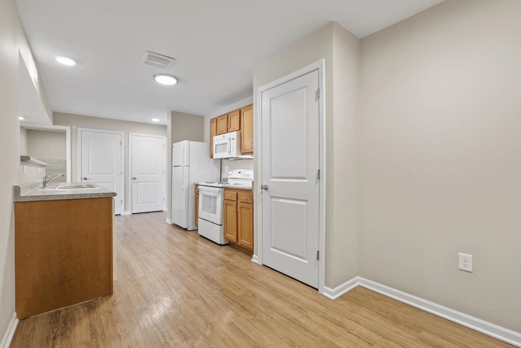 a renovated kitchen with white appliances and wood floors