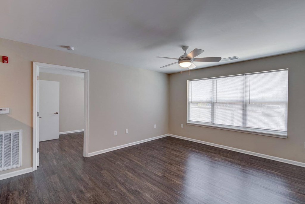 an empty room with a ceiling fan and a large window