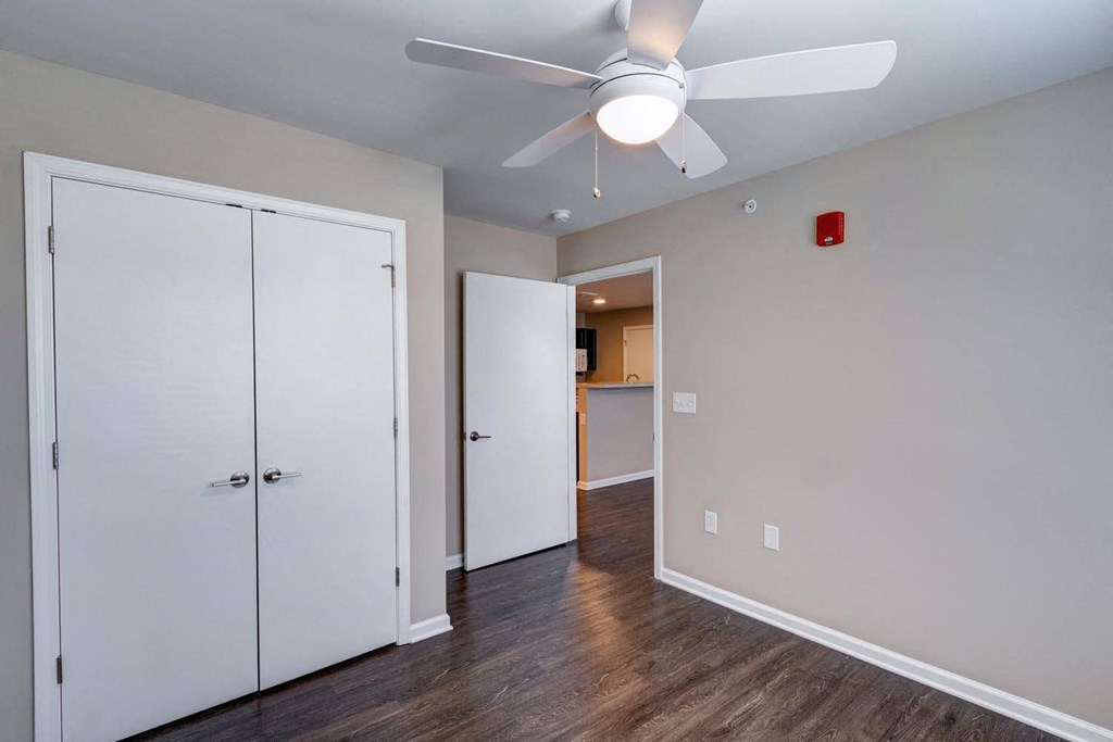 a bedroom with a ceiling fan and a door to a bathroom