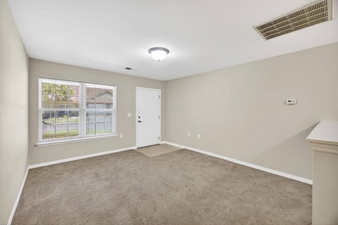 A room with a carpeted floor and a window showing an outdoor pool.