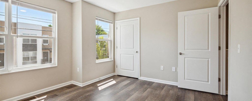 an empty room with two windows and a door