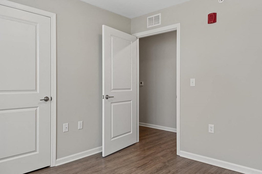 a bedroom with white doors and a door to an open closet