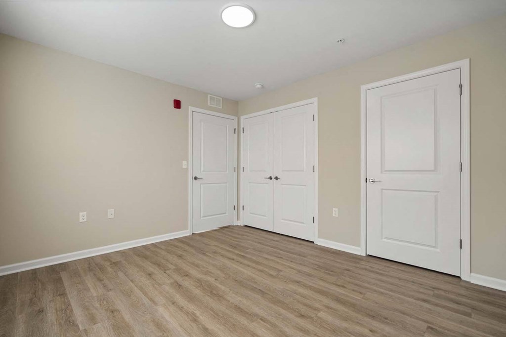 a bedroom with three doors and a hard wood floor