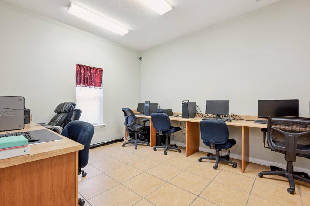 a group of desks with computers and chairs in a room