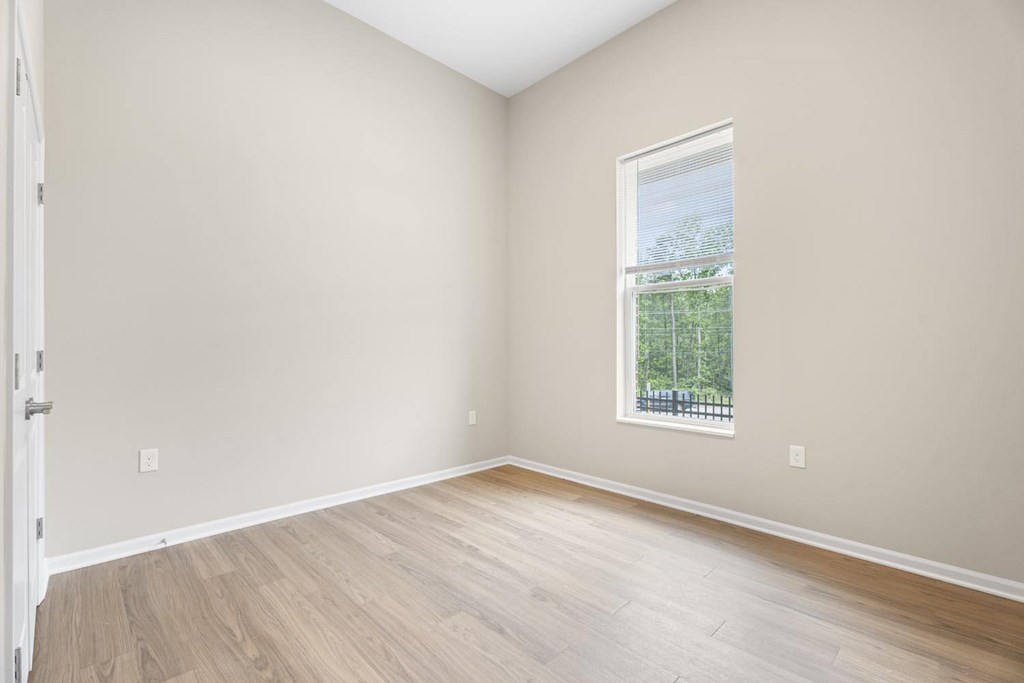 A room with a window and wooden flooring.