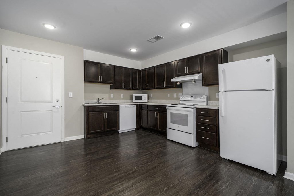 a kitchen with white appliances and dark wood cabinets