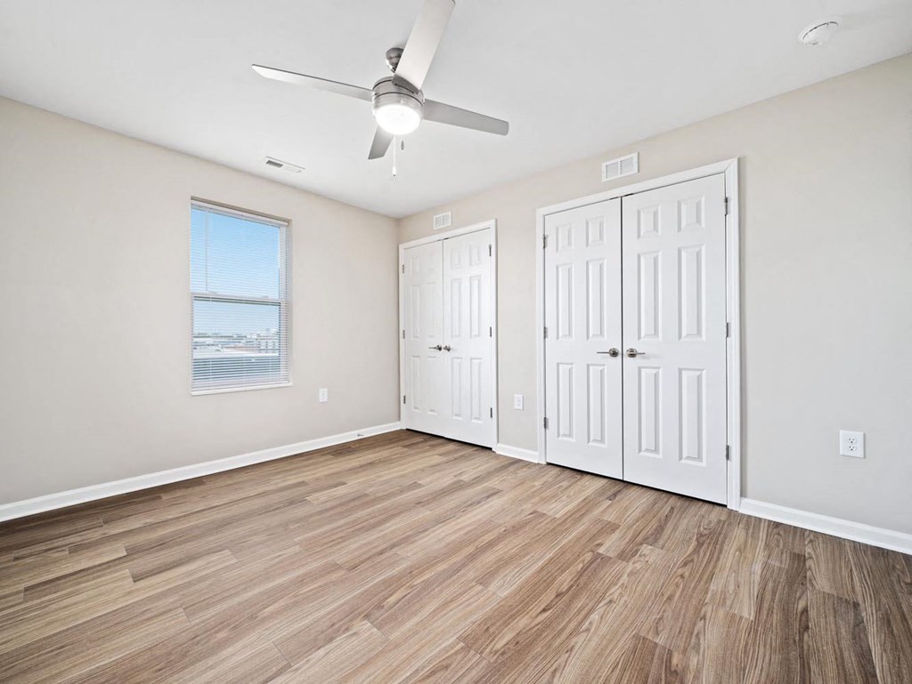 an empty living room with two doors and a ceiling fan