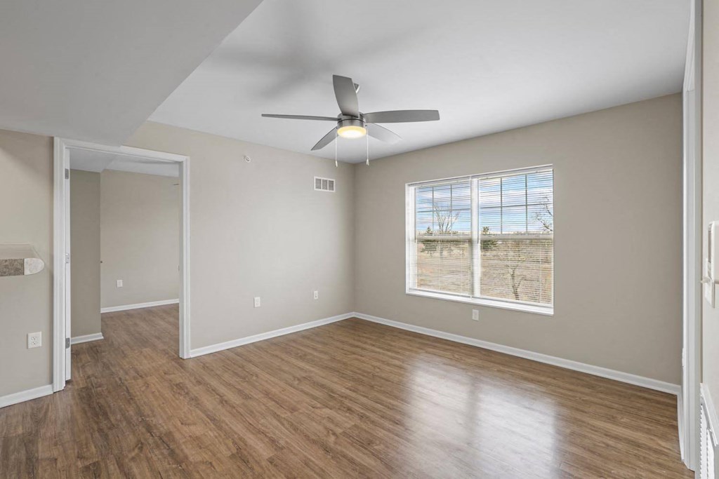 an empty living room with a ceiling fan and a window