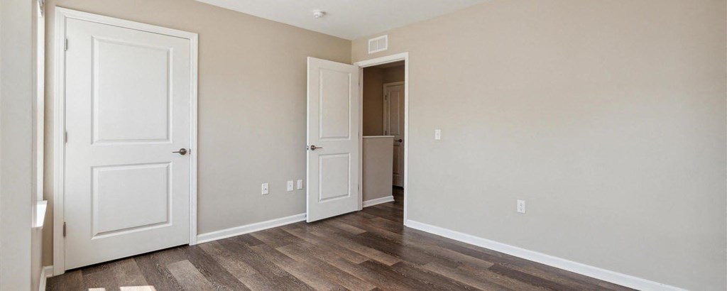 a bedroom with two doors and a bathroom in the background