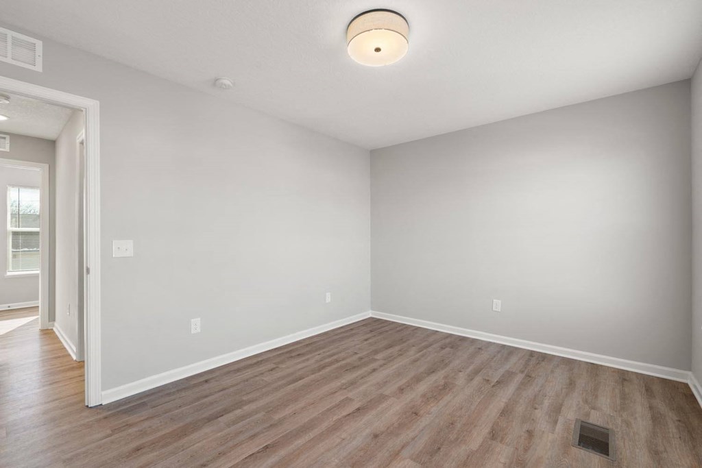 A room with a light on the ceiling and a doorway leading to another room.