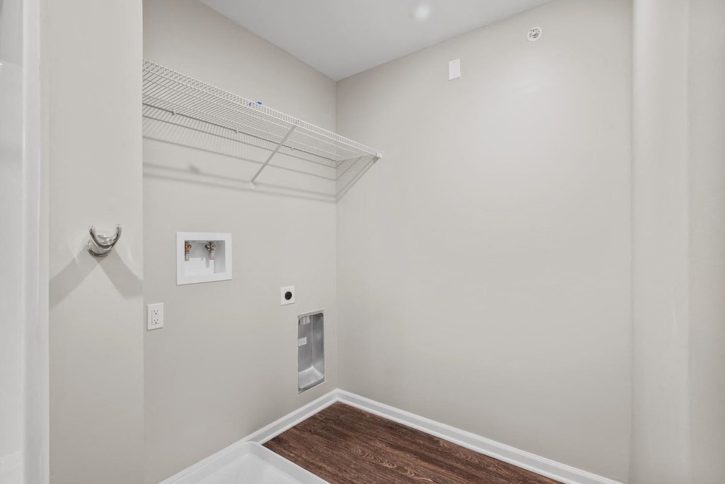 A room with a white wall and a brown floor.