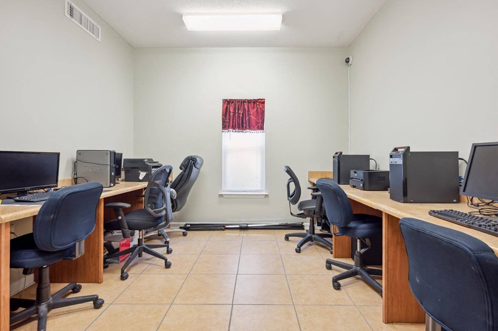 a group of desks with computers and chairs in a room