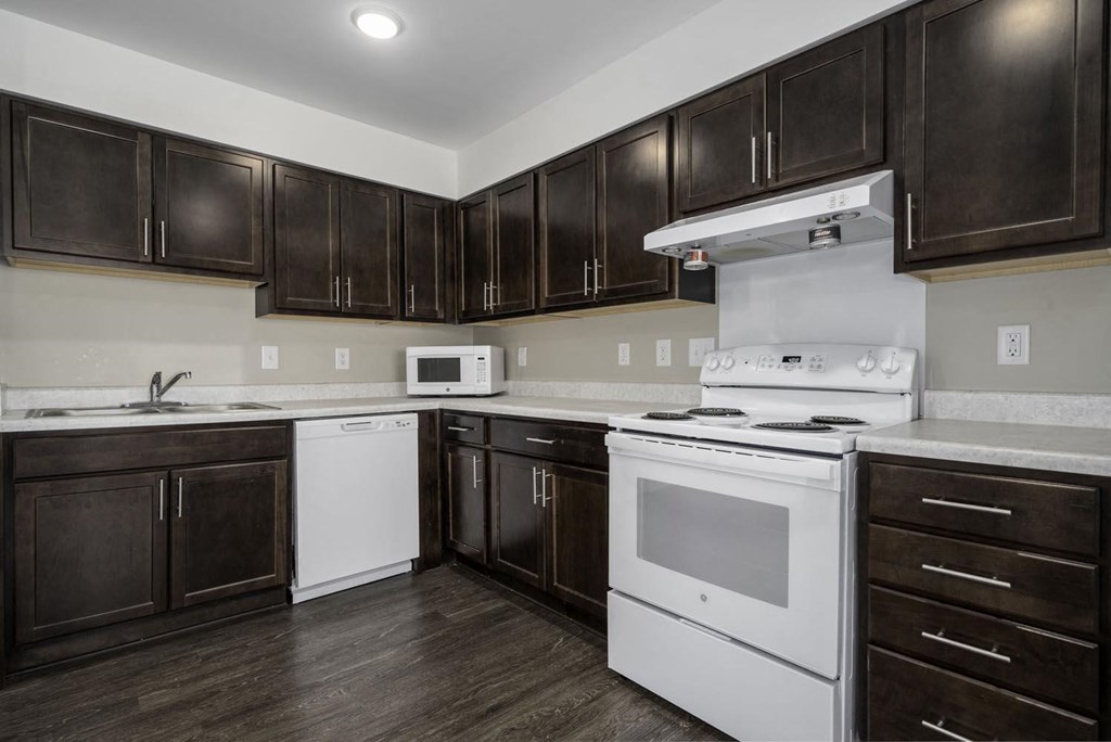a kitchen with white appliances and dark wood cabinets