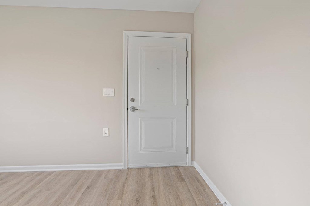 an empty room with a white door and a wooden floor