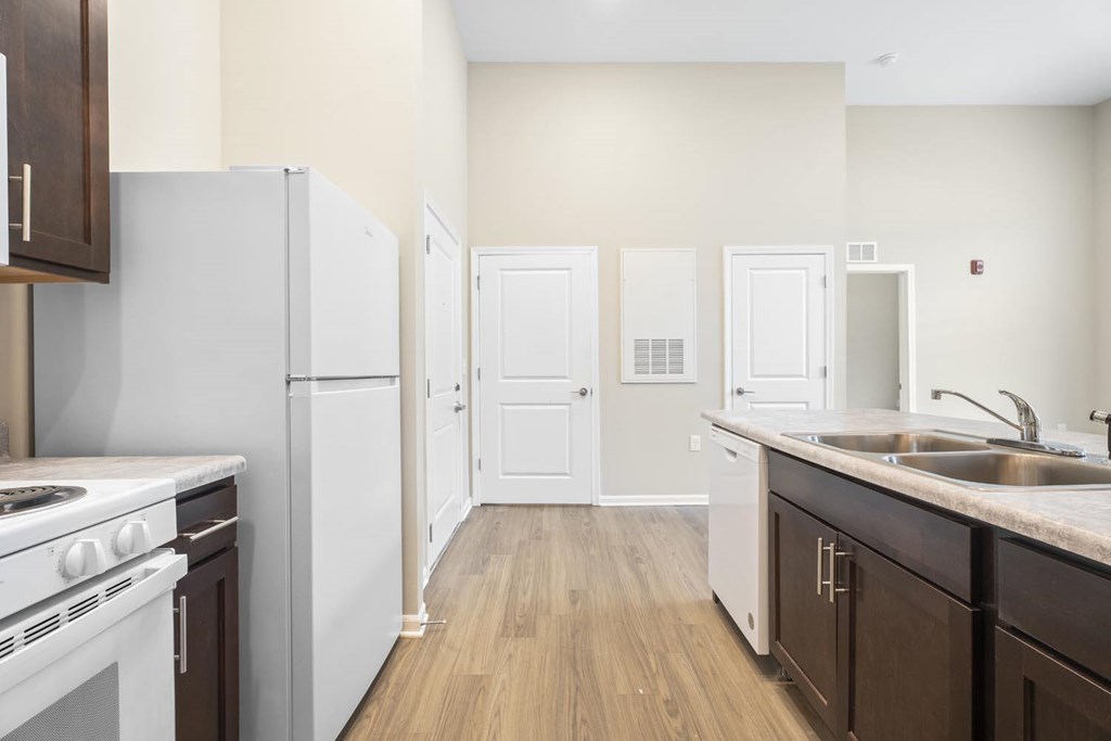 A kitchen with white appliances and brown cabinets.