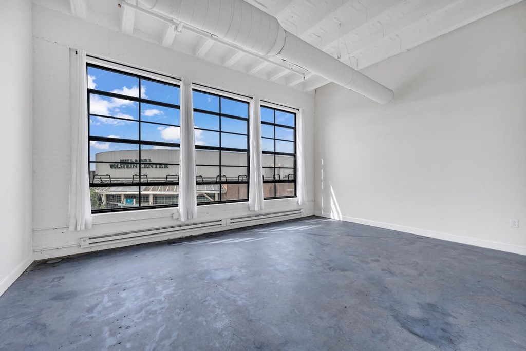 an empty room with large windows and a view of a train station