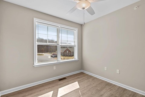 A room with a window overlooking a street with houses.