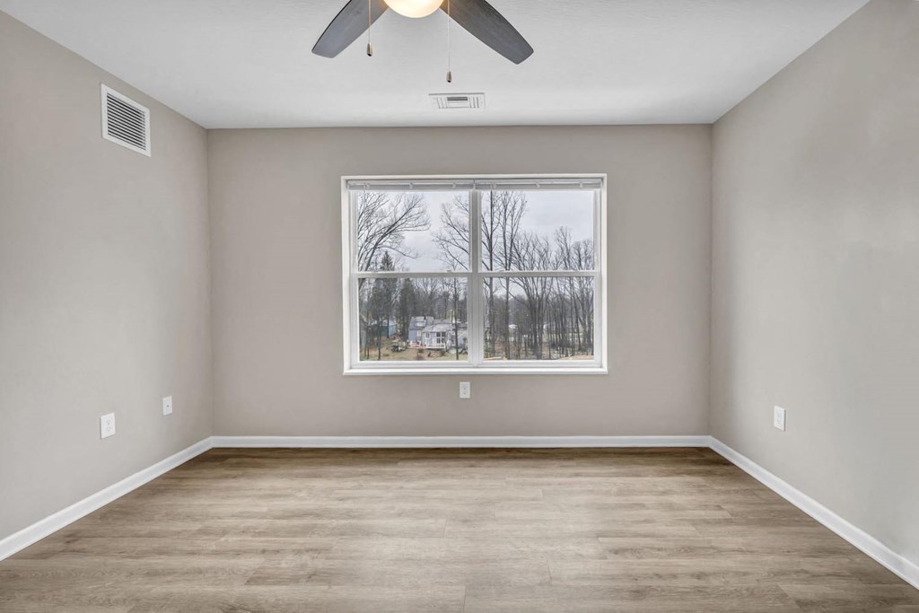 an empty room with a window and a ceiling fan