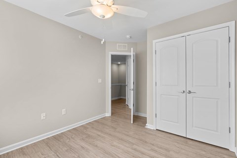 A room with a ceiling fan and a doorway leading to a bathroom.