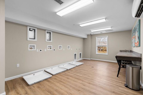 A room with a long table and chairs, and a window with a view of trees outside.