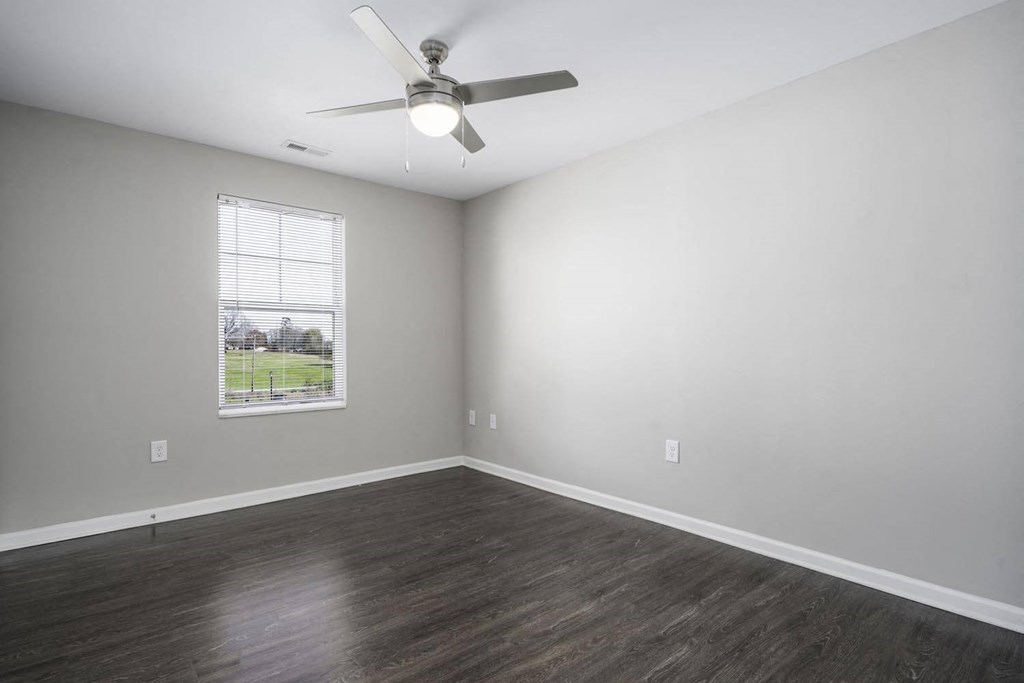 an empty living room with a ceiling fan and a window