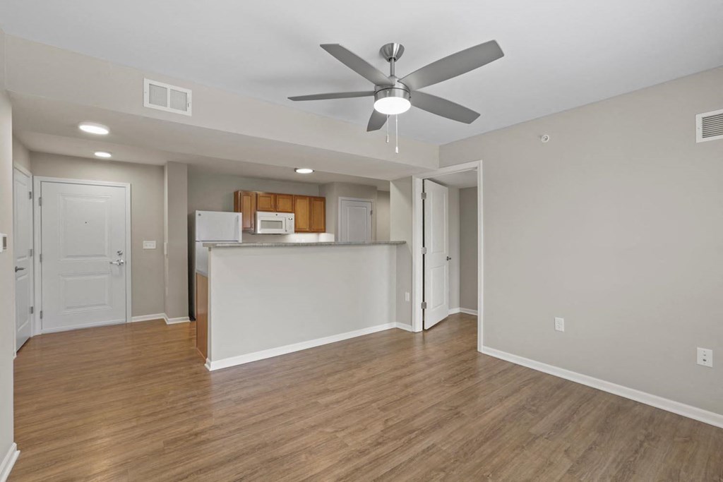 an empty living room and kitchen with a ceiling fan