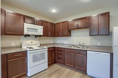 A kitchen with brown cabinets and white appliances.