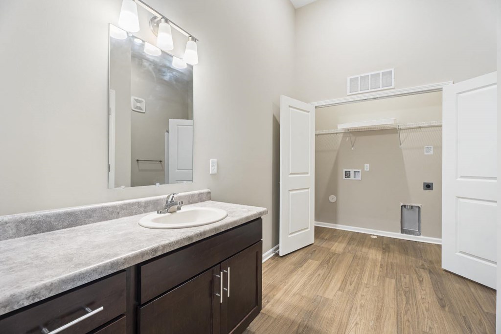 A bathroom with a sink, mirror, and wooden floor.