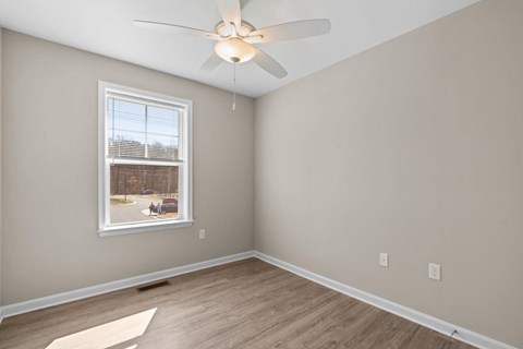 A room with a ceiling fan and a window showing an outdoor scene.