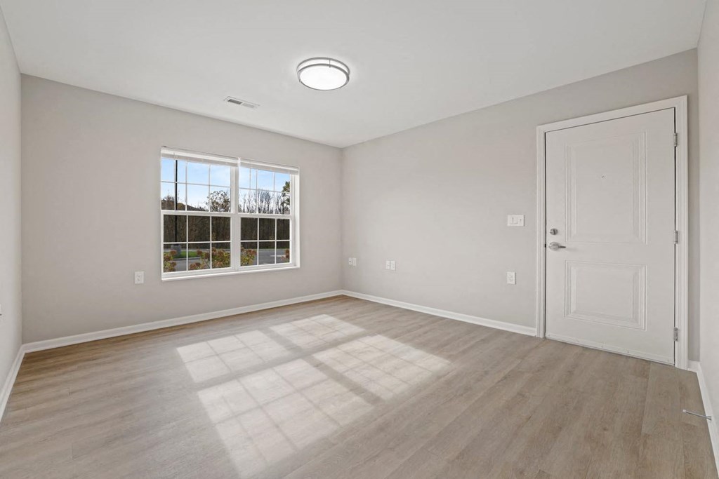 an empty living room with a white door and a window