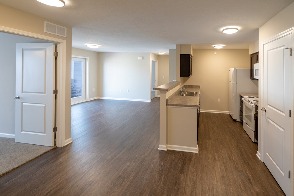 an empty kitchen and living room with wood flooring and an open floor plan