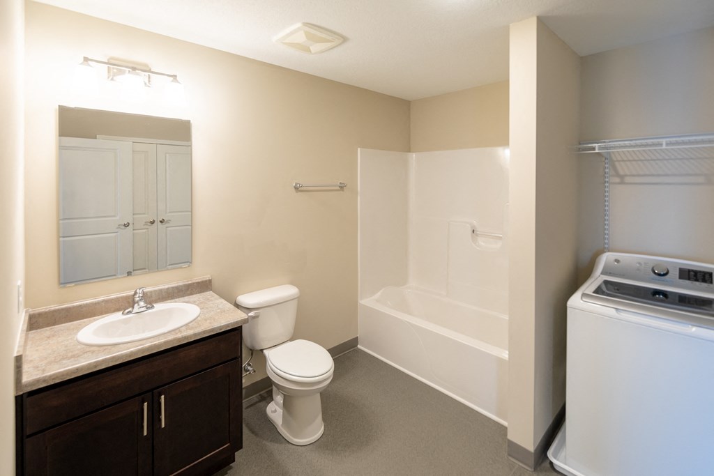a bathroom with a sink toilet and tub and a washer and dryer