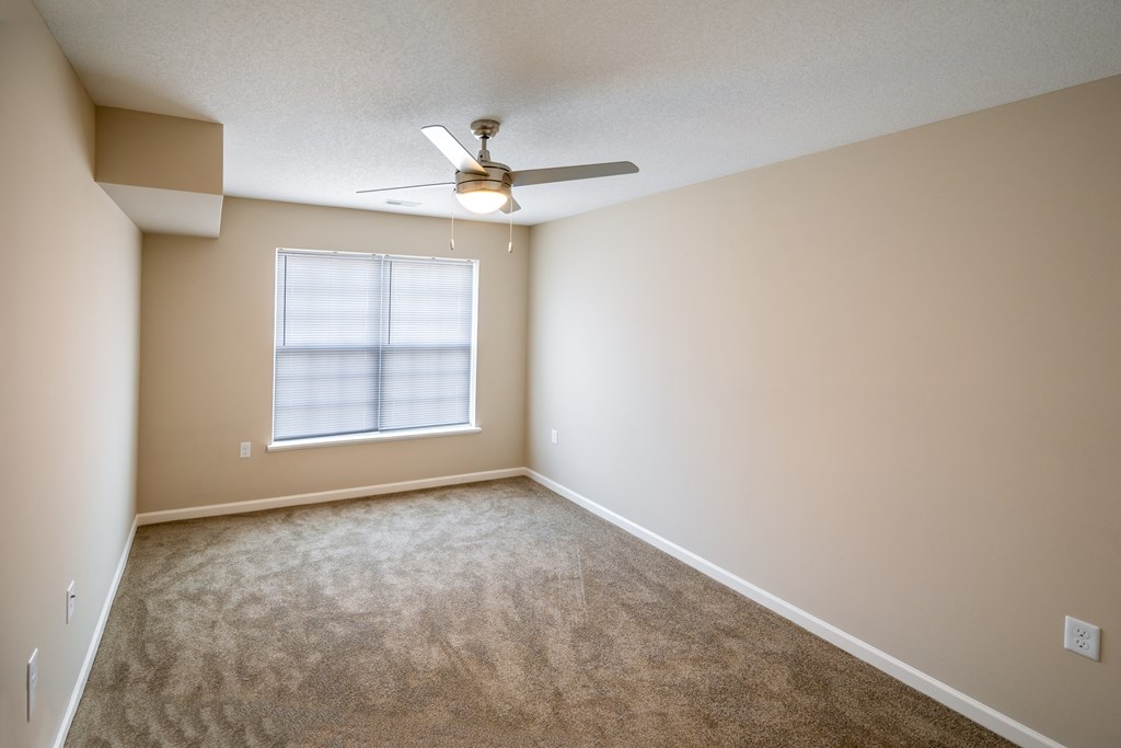 an empty living room with a ceiling fan and a window