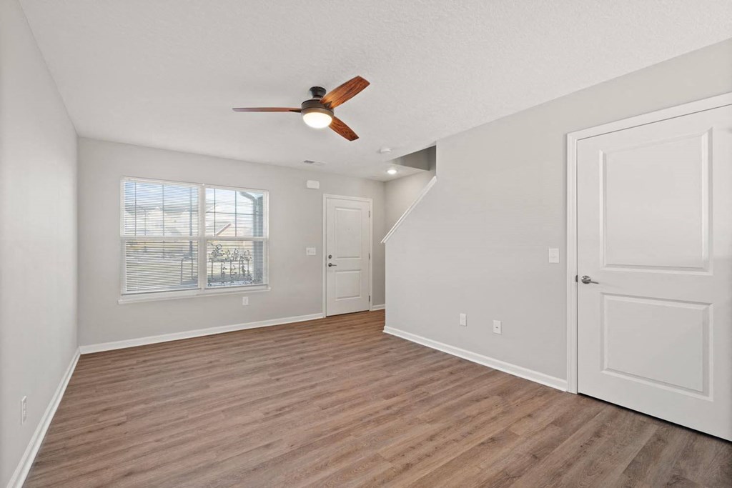 A room with a ceiling fan and wooden flooring.