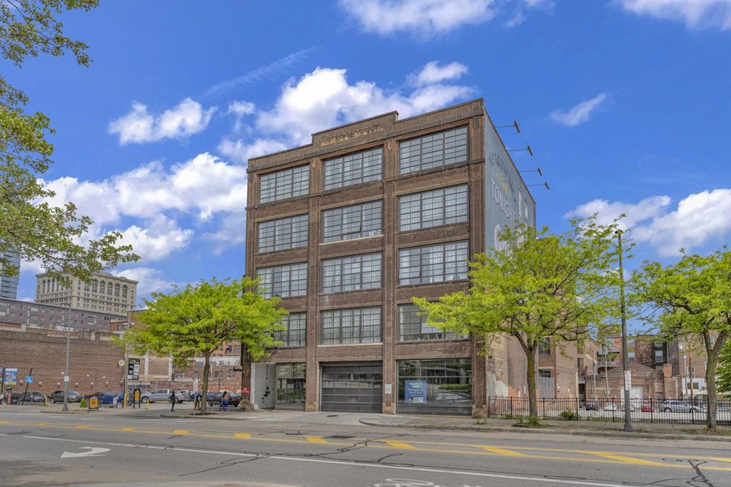 a six story brick and glass building on a city street with trees in front of it