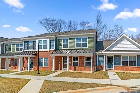 A row of houses with green and red brick and white trim.