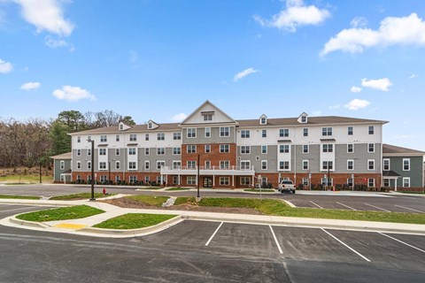 A large apartment complex with a parking lot in front.