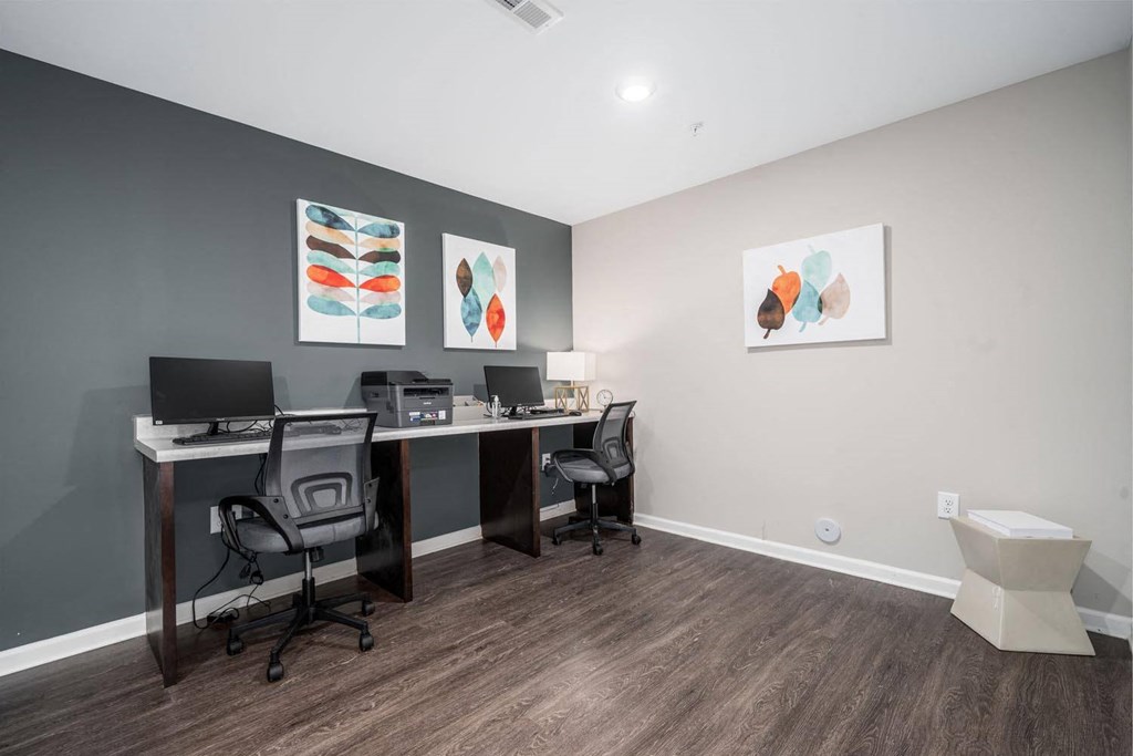 a home office with two desks and two chairs and paintings on the wall