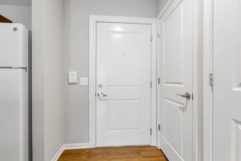a hallway with a white door and a refrigerator