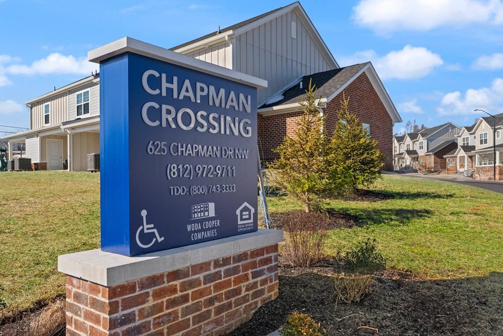 A sign for Chapman Crossing stands in front of a building.