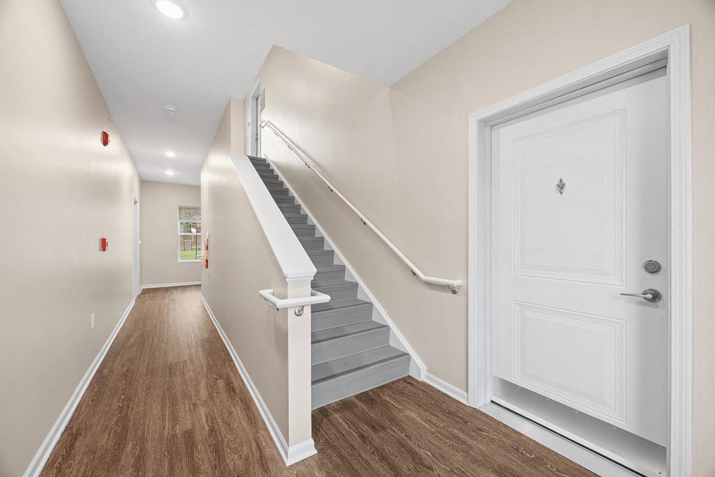 A hallway with a staircase and a white door.