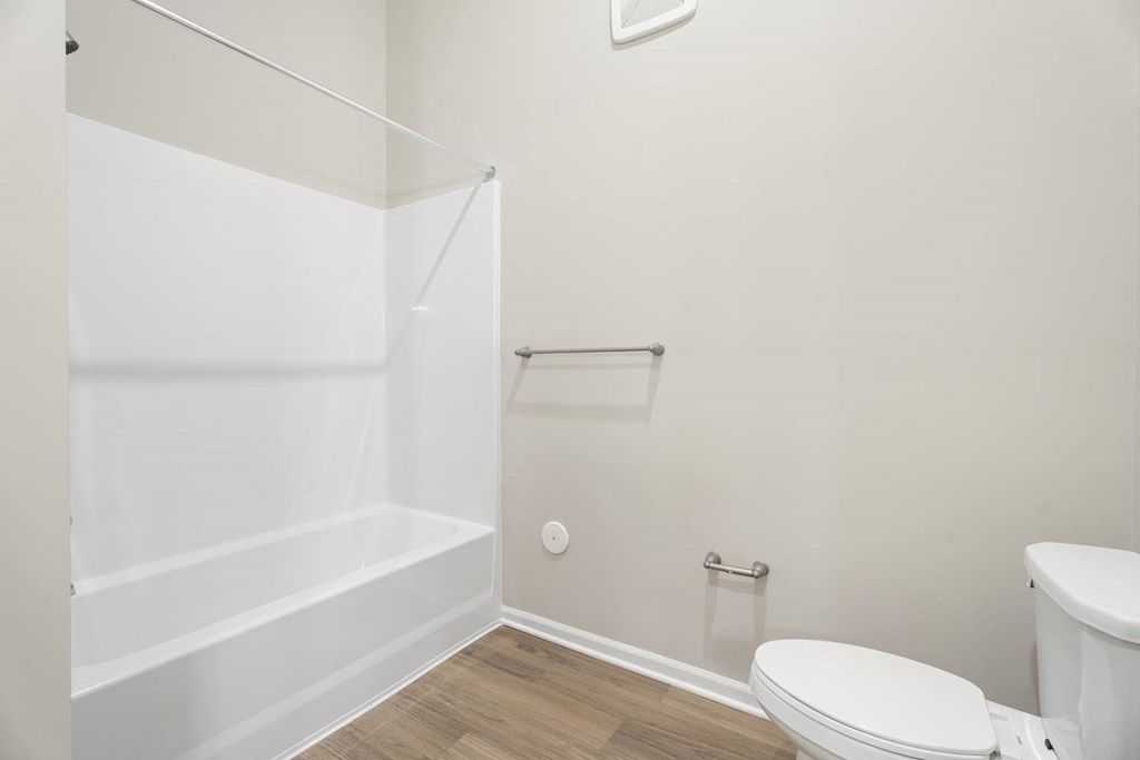 A white bathroom with a toilet, tub, and shower.